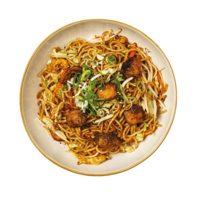 Ramen saltati con carote, zucchine, germogli di soia, cipollotto, tofu fritto, servito con salsa teriyaki e mayo vegana, semi di sesamo ed erba cipollina.